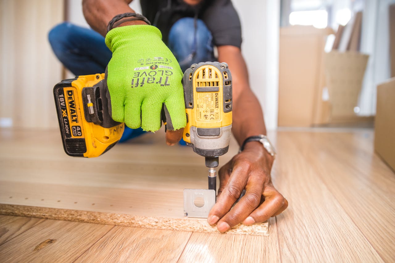 gallery-5 Man using a power drill for home improvement on a wooden floor with precision.