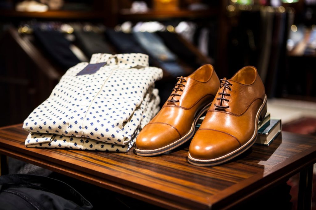 pexels photo 298863 Elegant brown leather shoes and printed shirt displayed on a wooden table in a stylish clothing store.