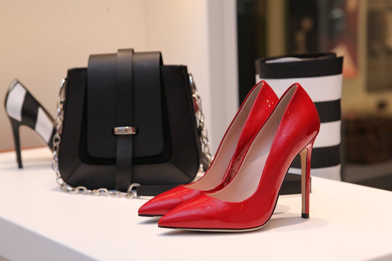 about-img Showcasing sleek red stilettos and a chic black handbag in a luxury boutique setting.